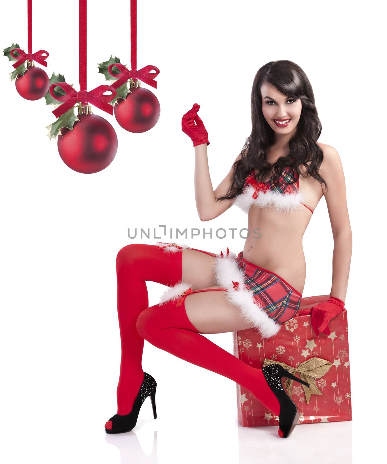 glamour shot of a smiling christmas girl wearing a sexy outfit and sitting on a huge red giftbox