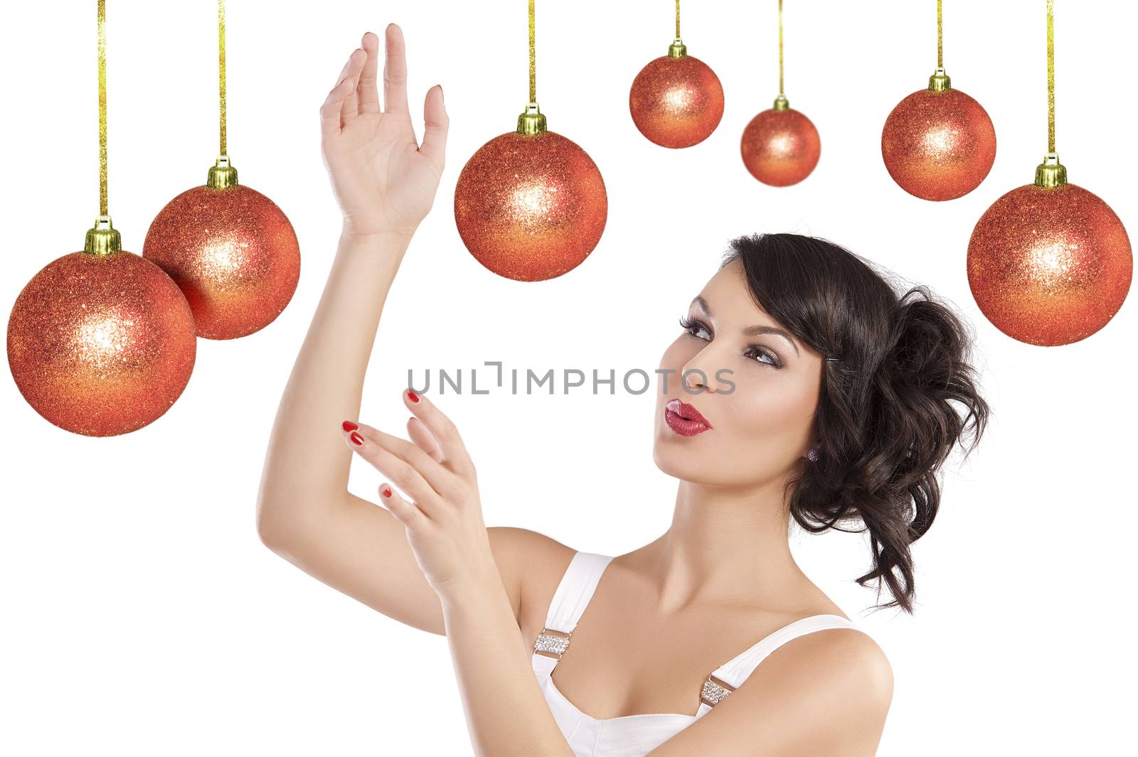 Pretty brunette with hair style and a white dress between christmas ball playing in joyful mood