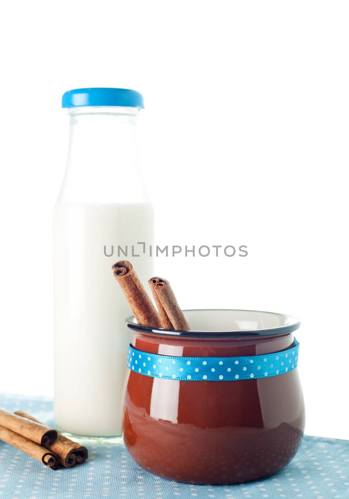 Brown mug, milk bottle, cinnamon on blue napkin