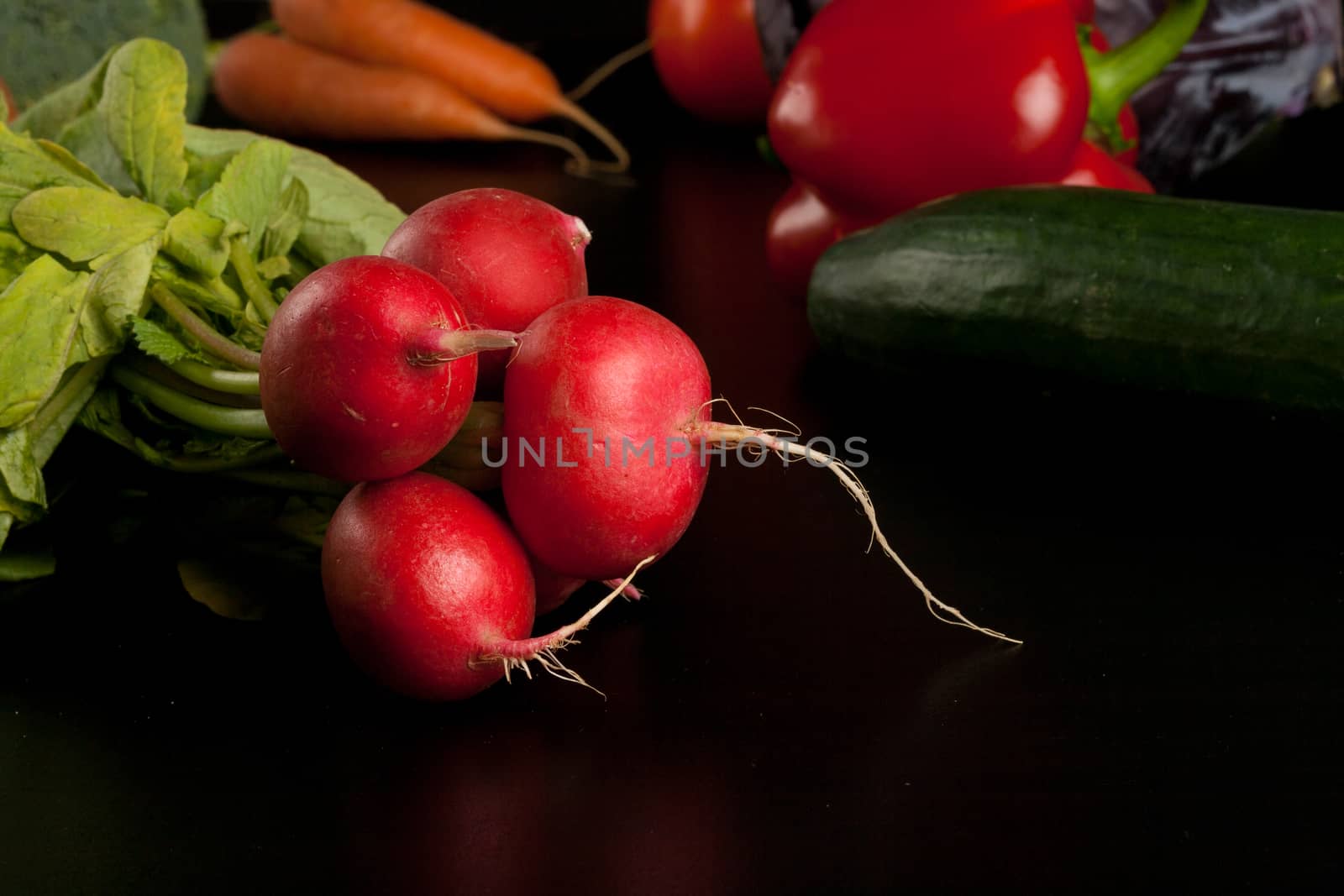 radish on black with different vegetables in the background