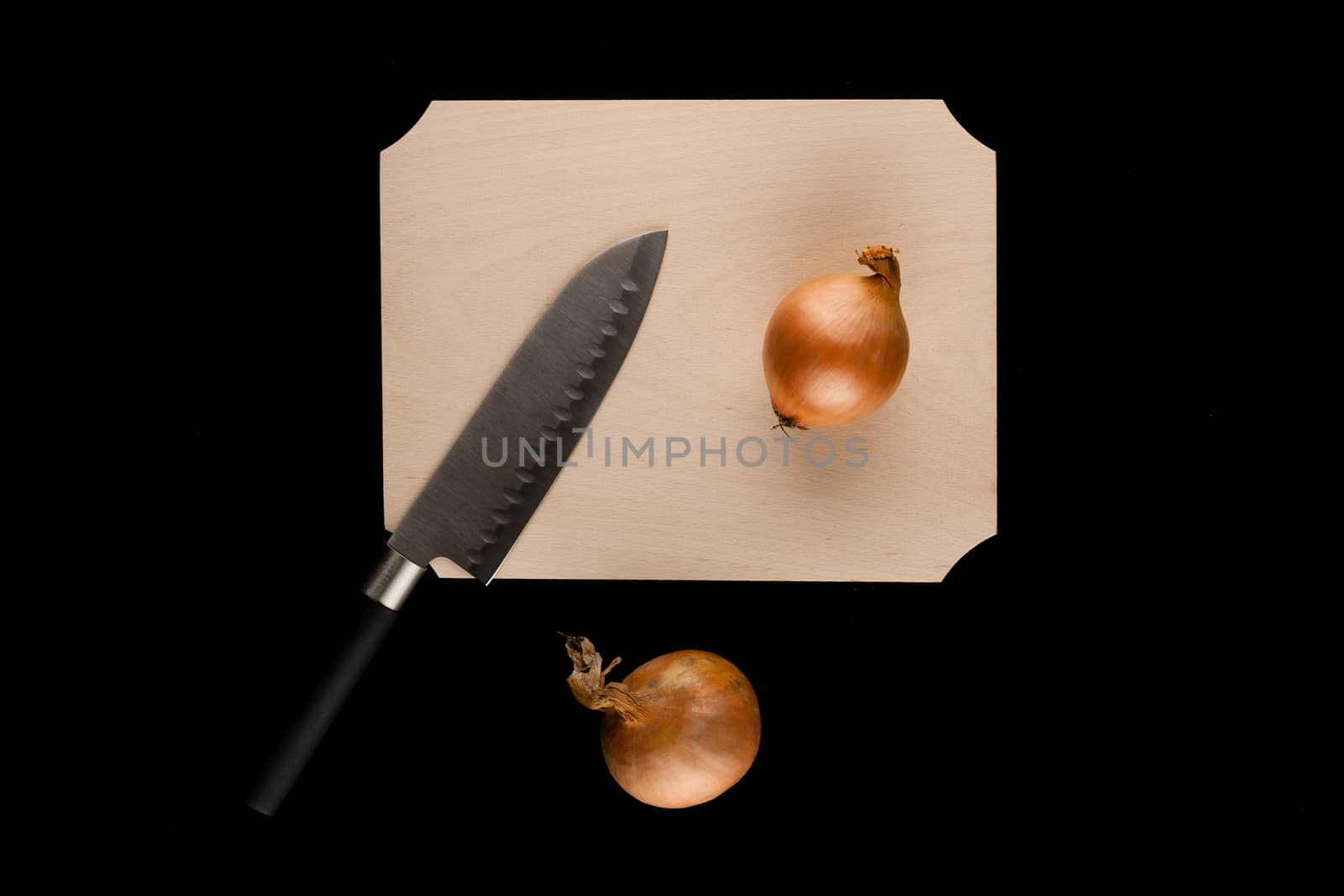 onions with knife on wooden cutting board on black background