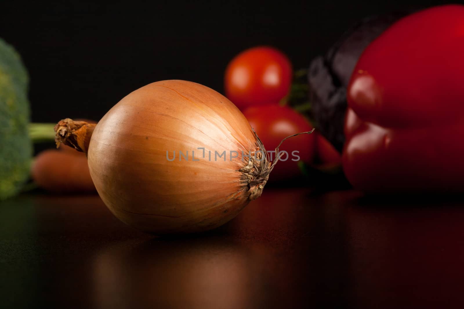 onion on black with different vegetables in the background