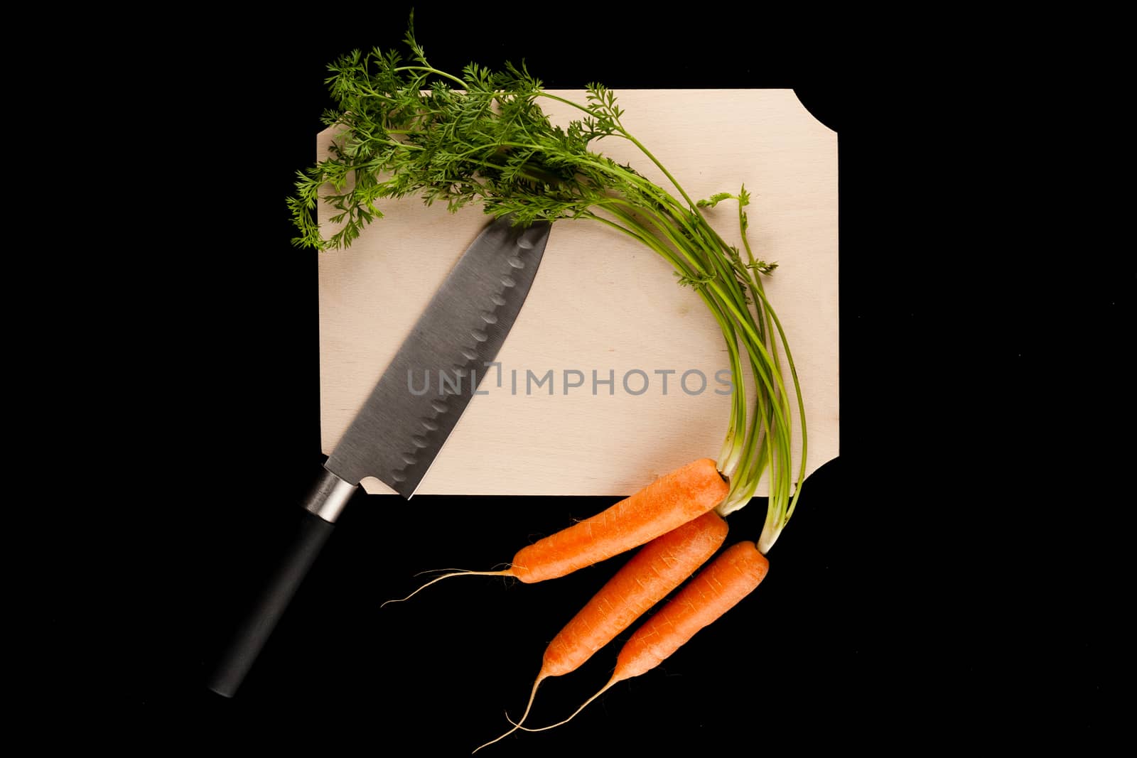 carrots with knife on wooden cutting board on black background