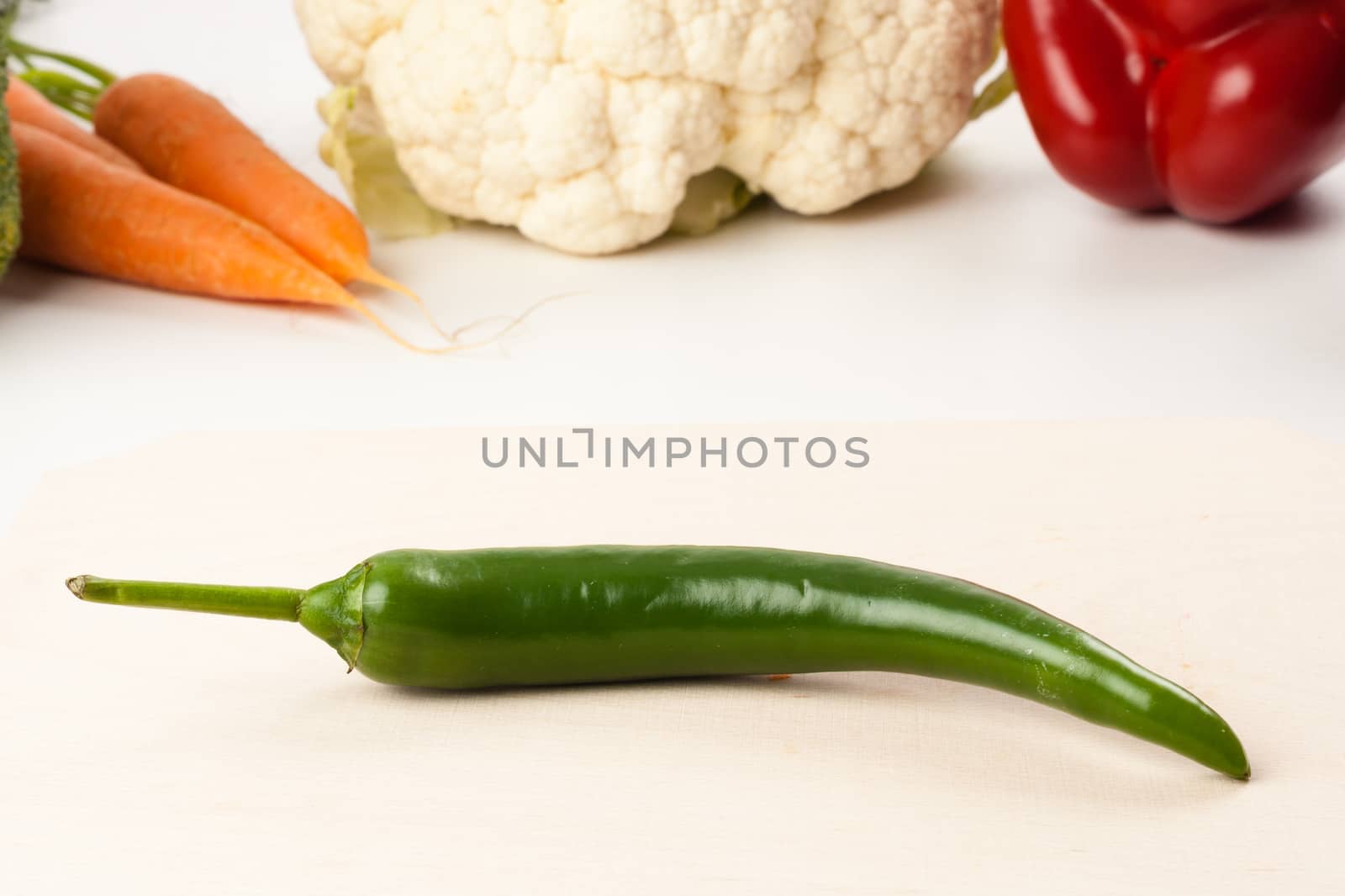 pepper on cutting board with different vegetables in the background