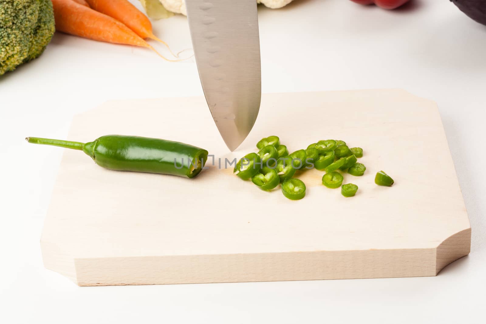 pepper on cutting board with different vegetables in the background