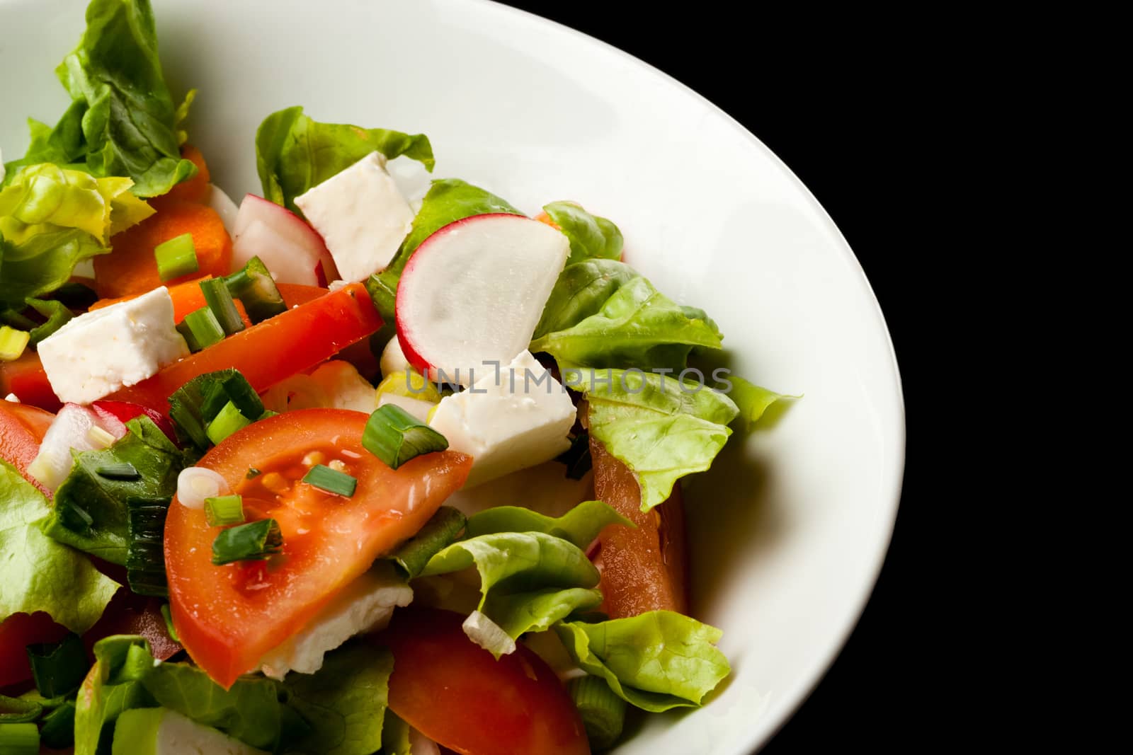 vegetable salad in white bowl on black background