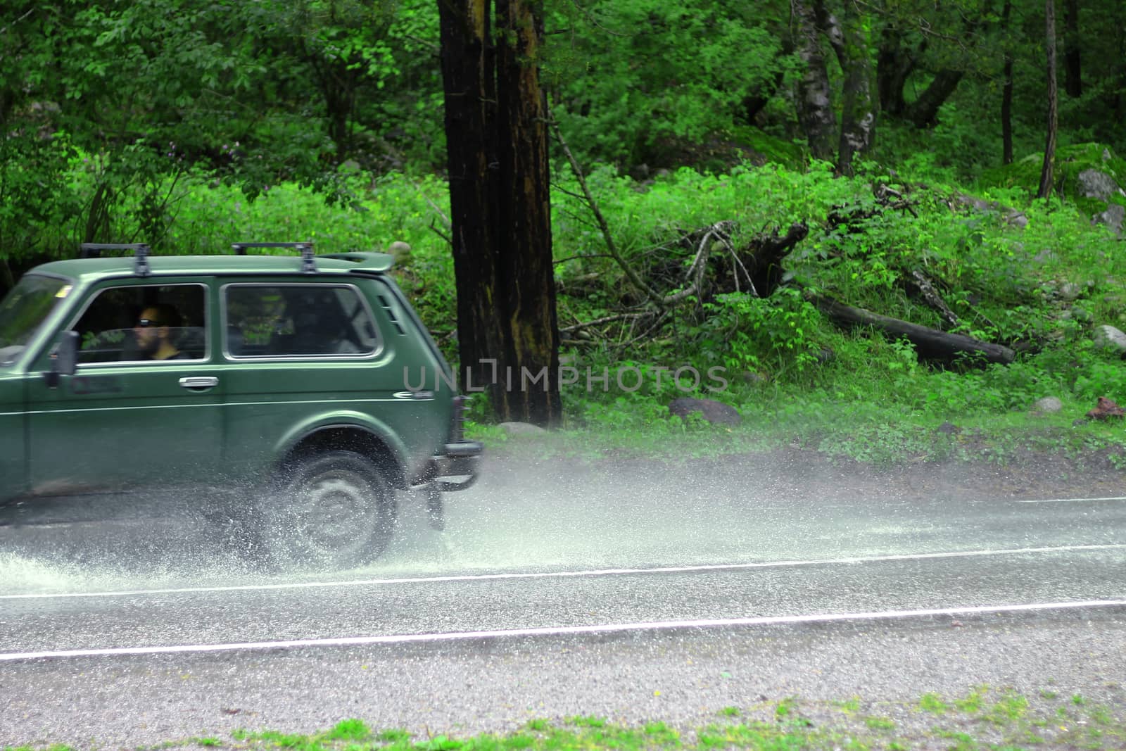 Automobile driving on the puddle on a highway