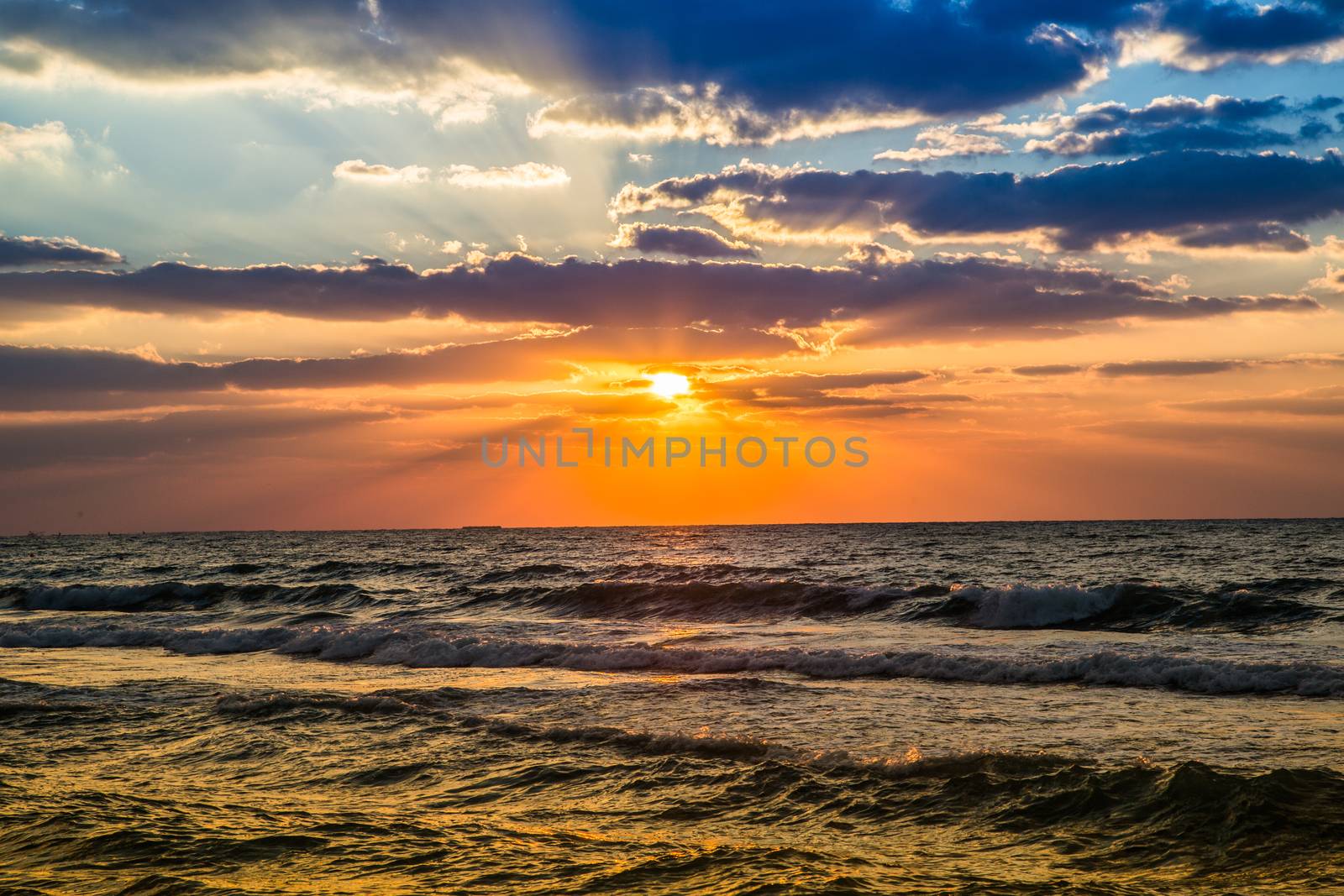 Beautiful sunset at the beach, amazing colors, light beam shining through the cloudscape over the arabian gulf seascape, united arab emirates. Dubai sea and beach