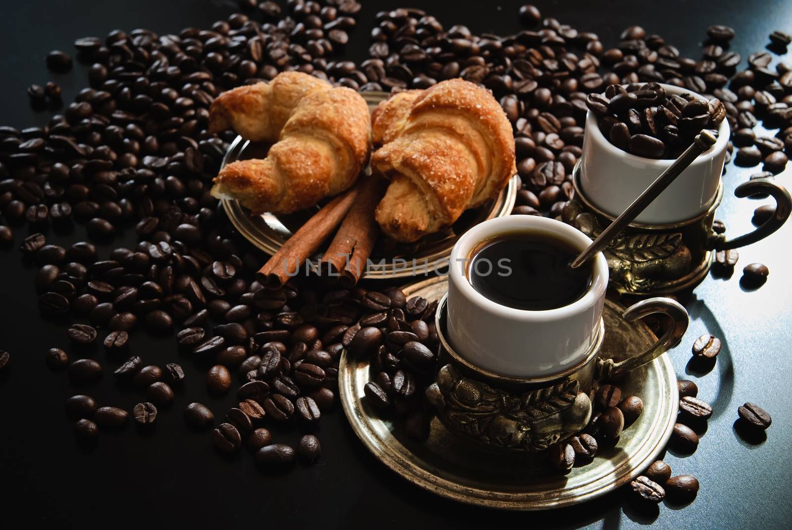 Two cups of coffee with croissants and pieces of cinnamon