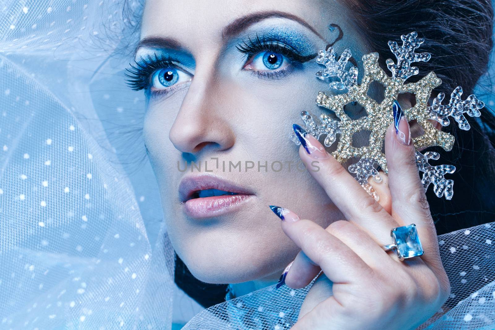 Girl with scenic make-up of the Snow Queen is holding a snowflake shot closeup