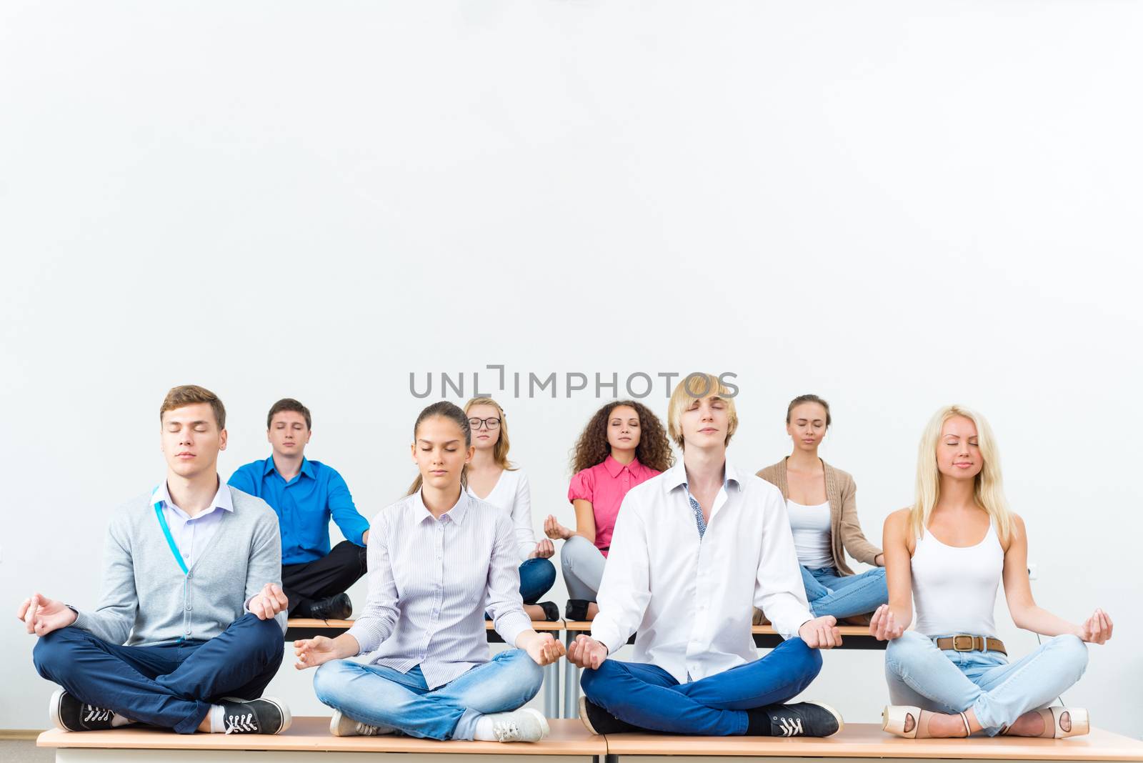group of young people meditating in office at desk, group meditation