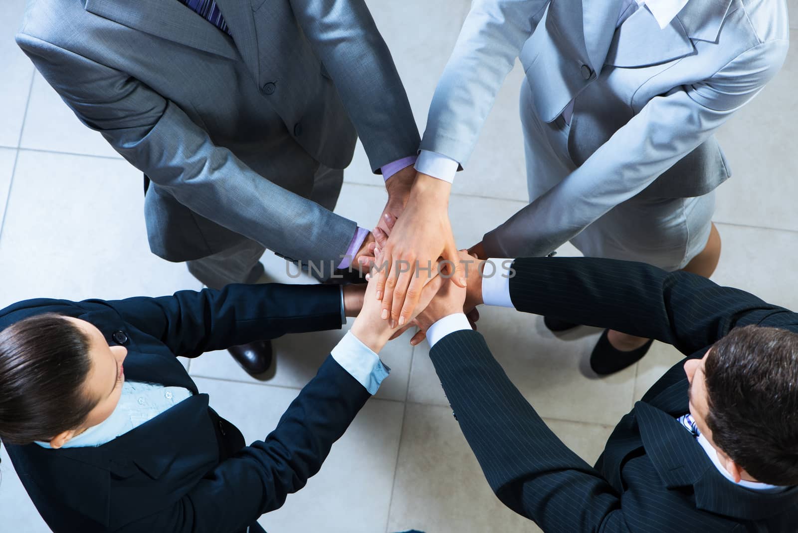 team of four businessmen with folded hands, a symbol of teamwork