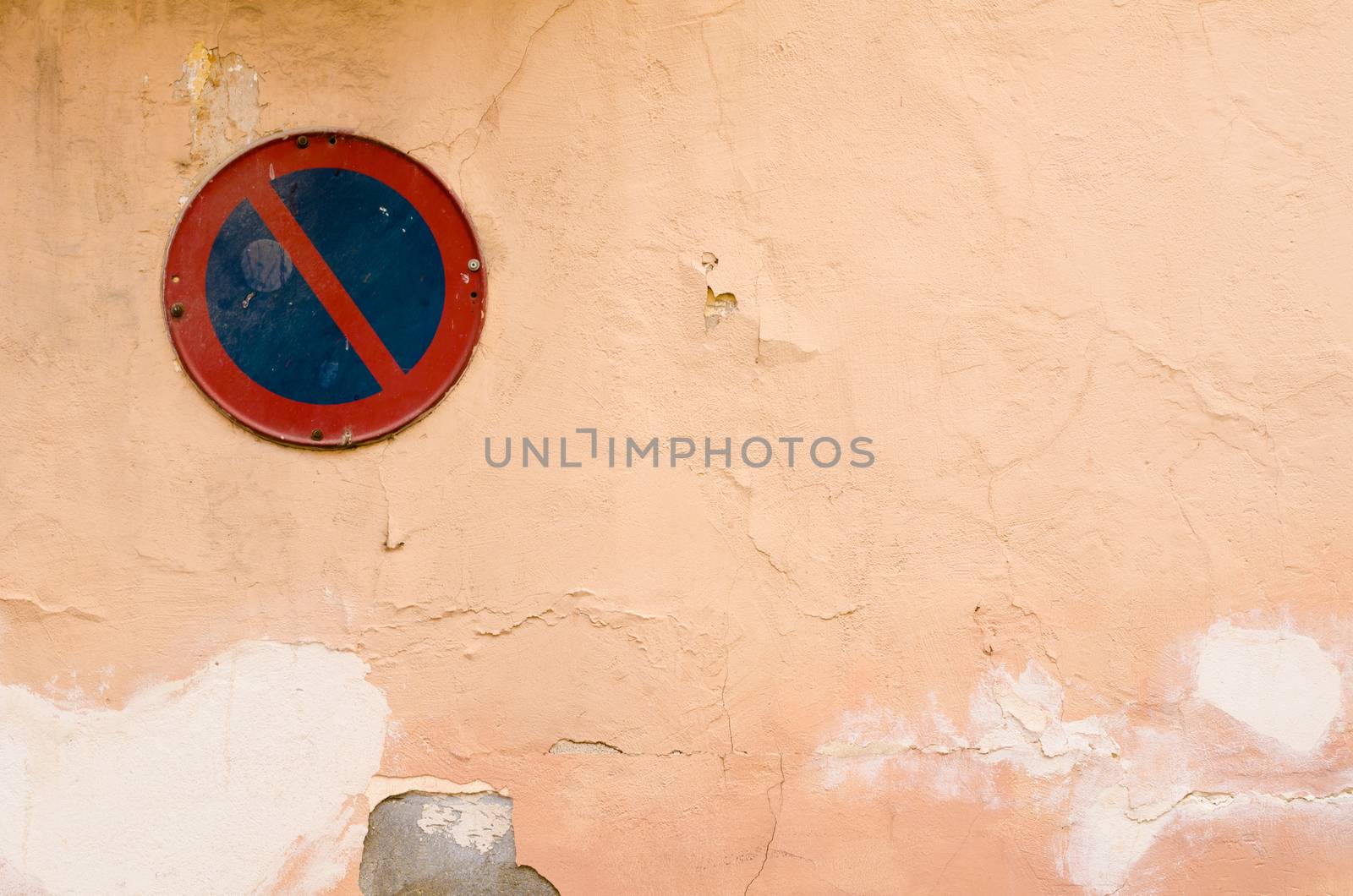 Old peeling wall with a no parking sign on it