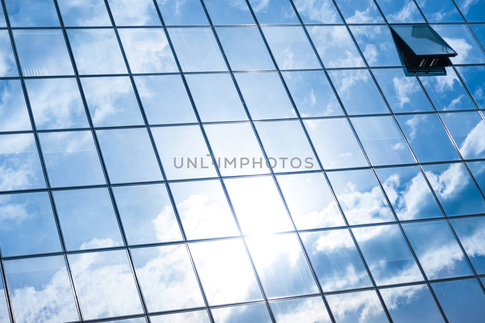 Modern facade of glass and steel with open window reflecting sky and clouds.