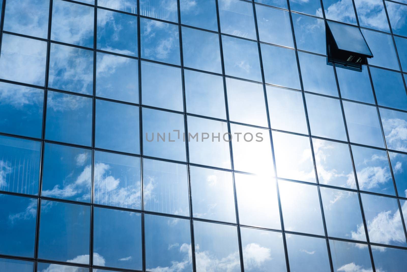 Modern facade of glass and steel with open window reflecting sky and clouds.