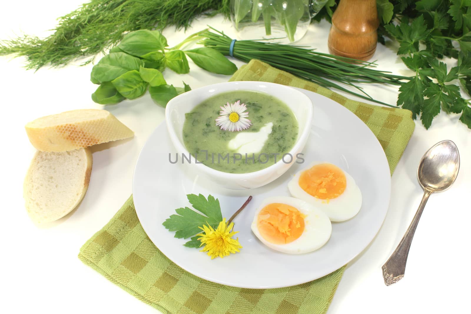 fresh herbs soup with eggs, a dollop of cream and daisy