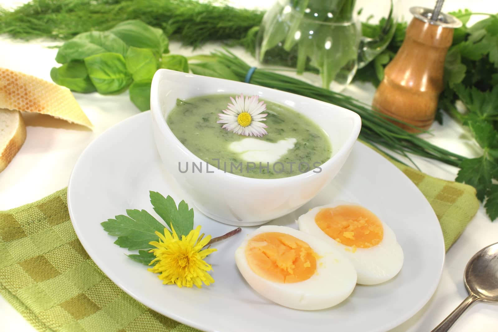 green herbs soup with eggs, a dollop of cream and daisy