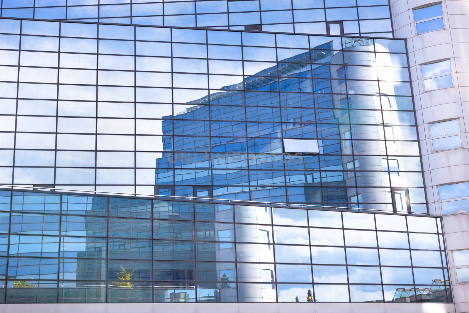 Modern facade of glass and steel with open window reflecting sky and clouds.