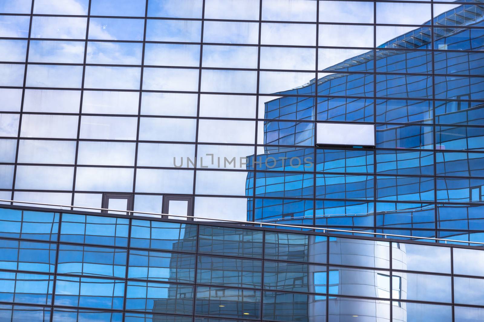 Modern facade of glass and steel with open window reflecting sky and clouds.