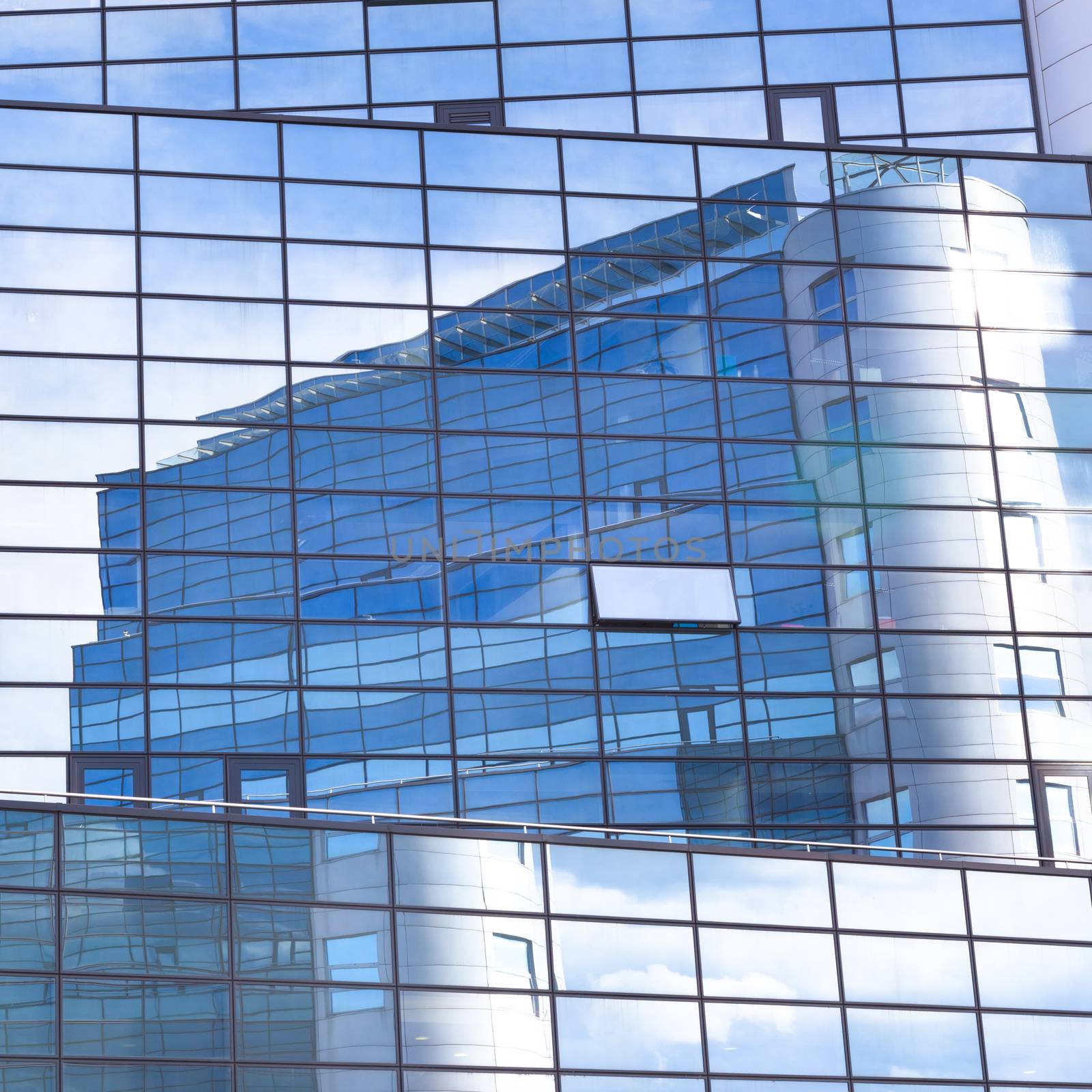 Modern facade of glass and steel with open window reflecting sky and clouds.