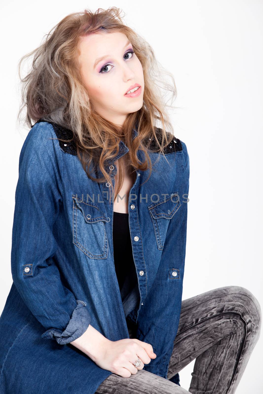 Young tough blond teenage girl with jeans blouse on a white background