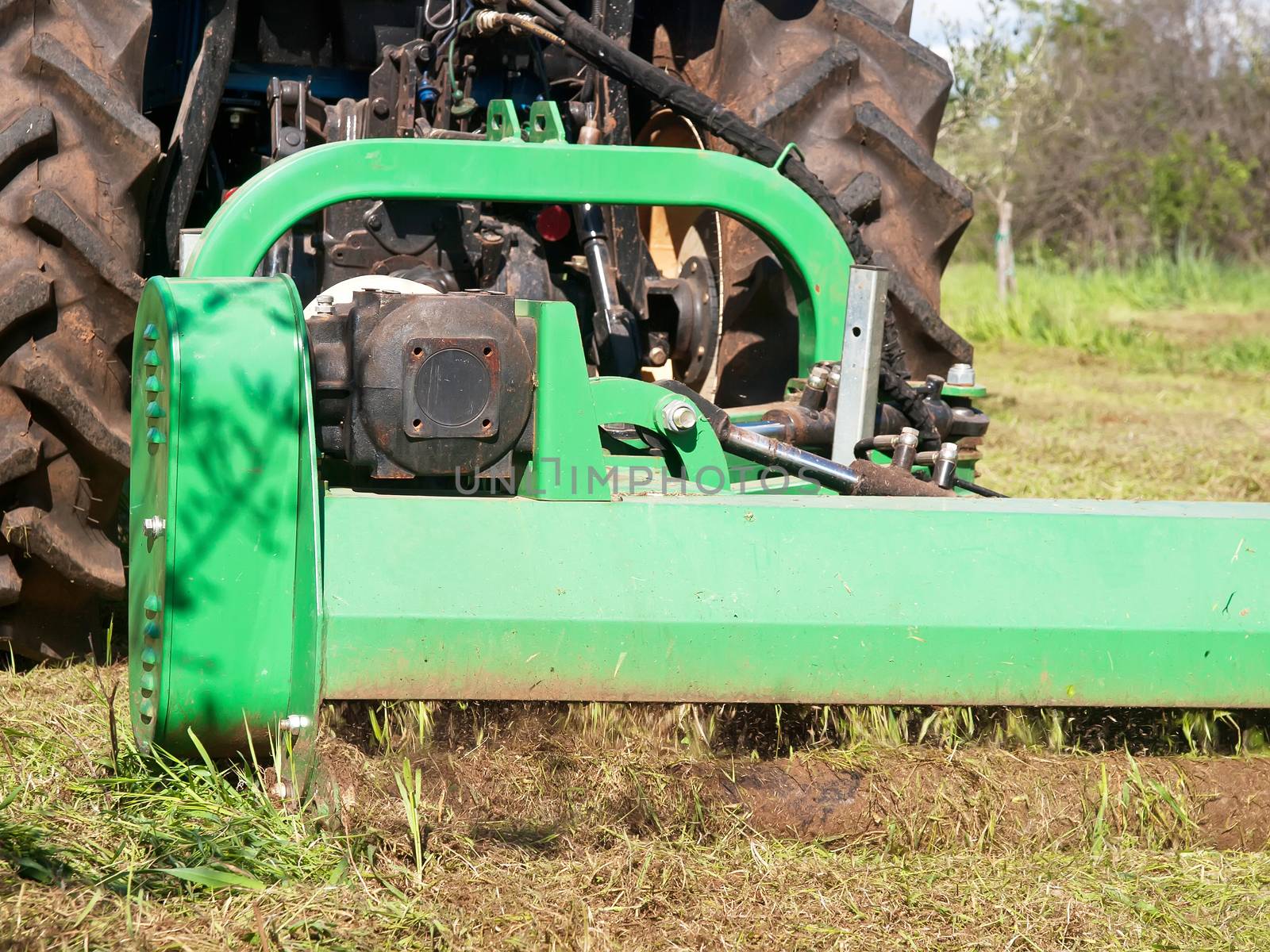 tractor machine lawnmower cutting grass along ground field