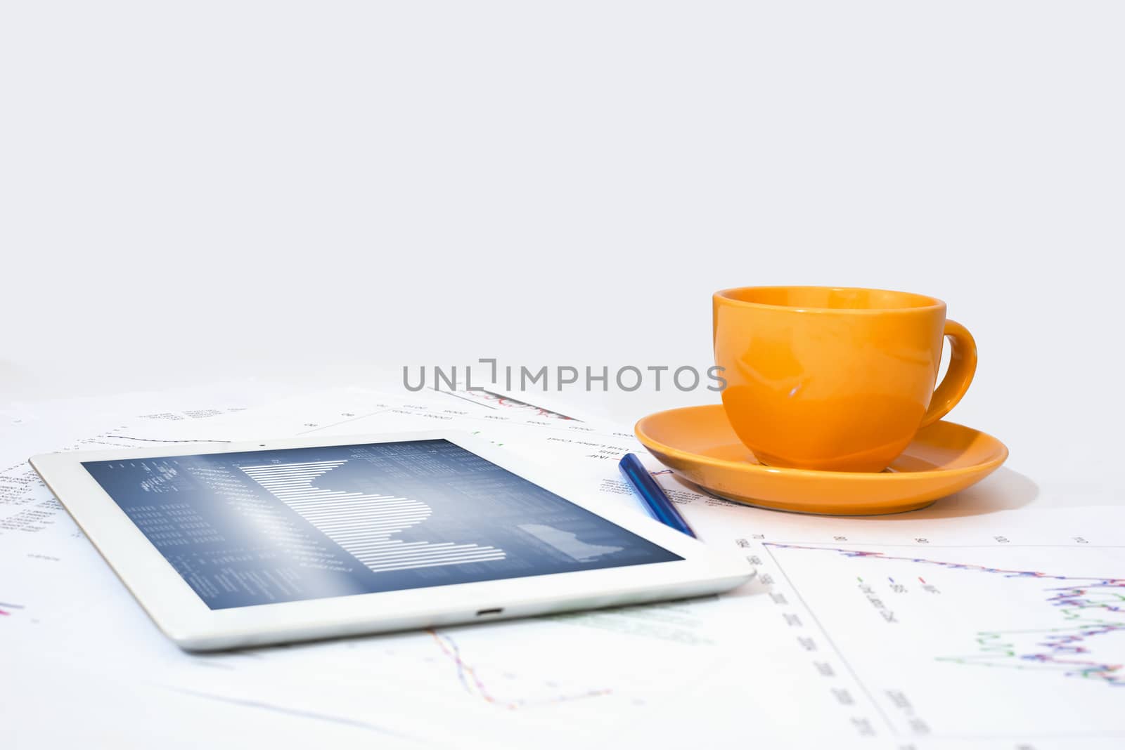 Tablet pc, orange cup and paper with graphs by cherezoff