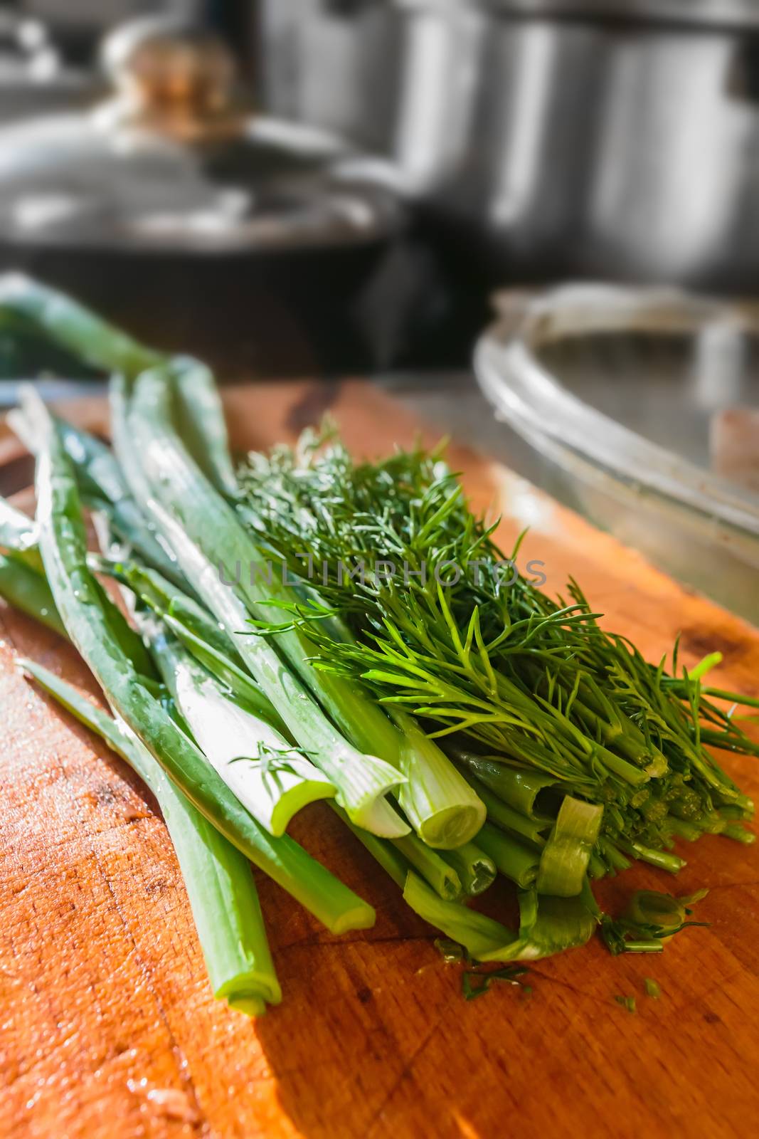Chopped green onions and dill on a wooden board