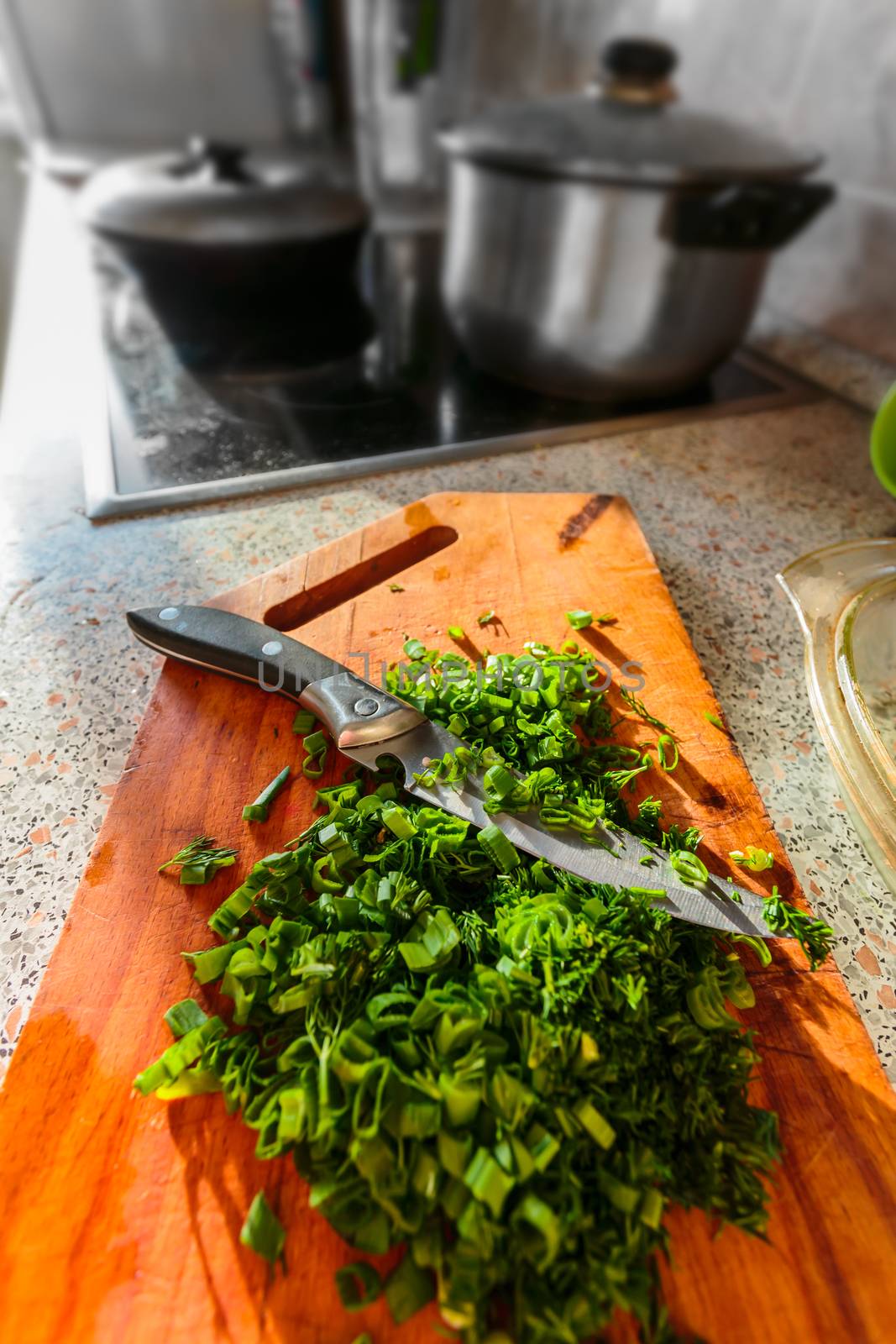 Chopped green onions and dill on a wooden board