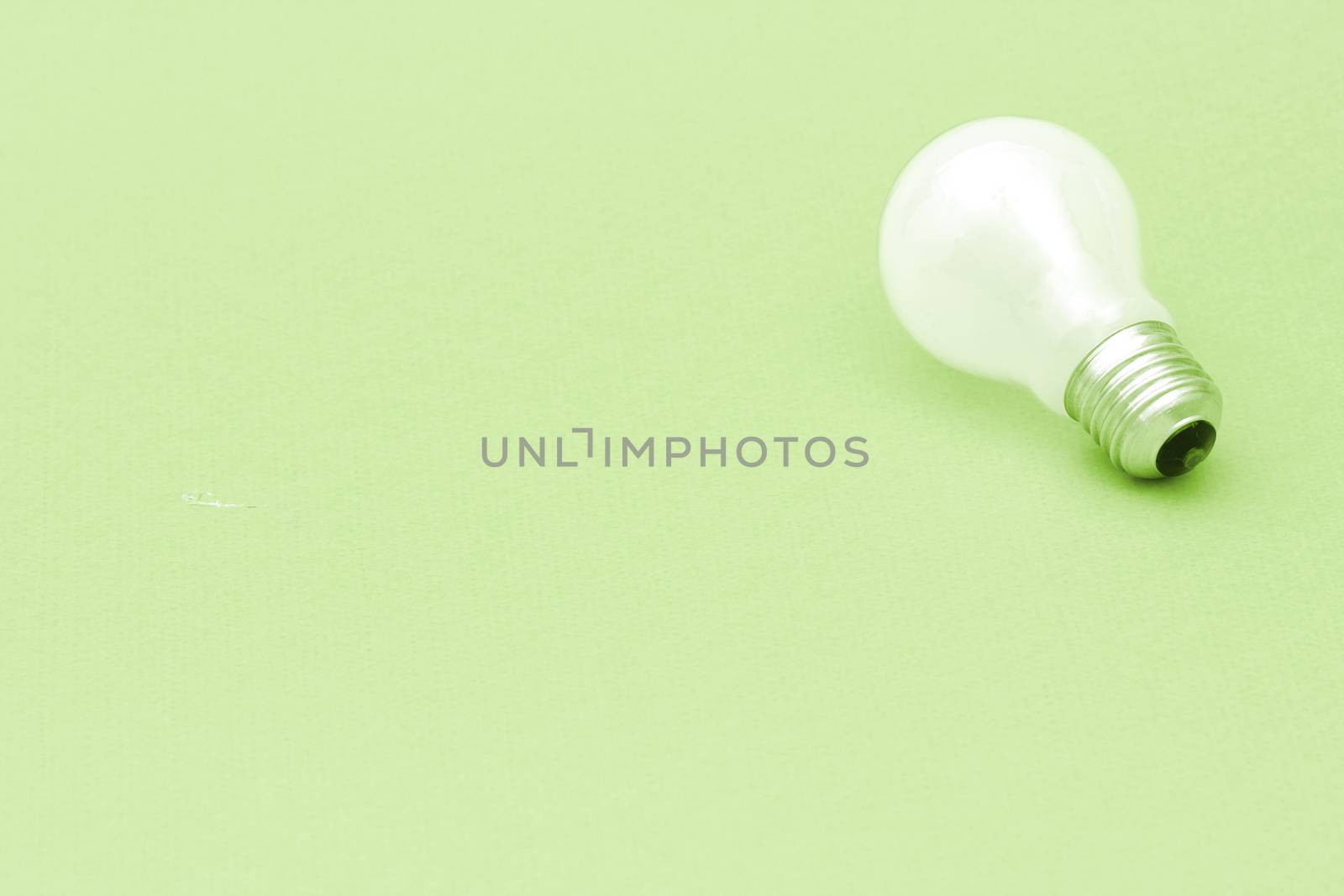 Background with lit lightbulb. Isolated on green