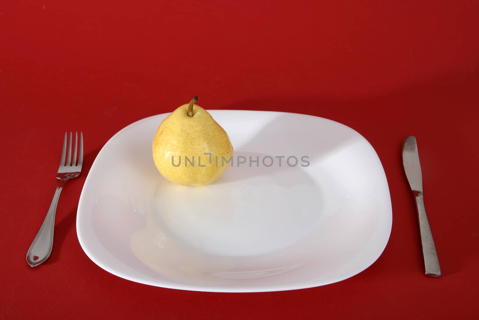 Tasty  yellow pear on a white plate.