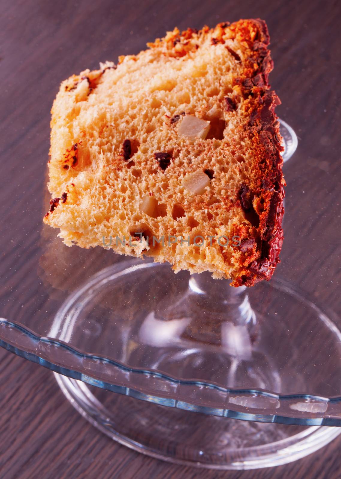 Chocolate cake over glass cake stand, wooden background