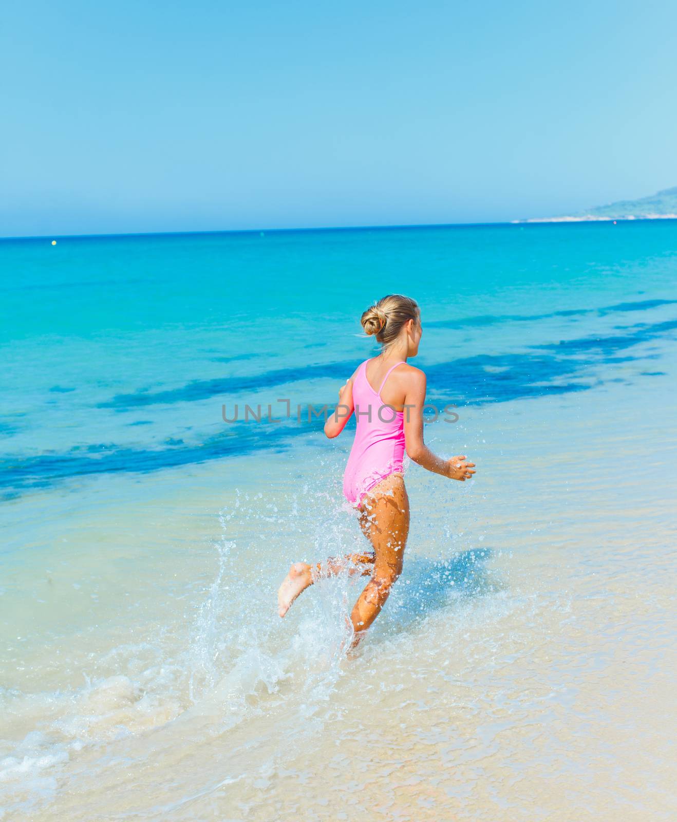 Beautiful happy smiling girl runs along the beach.