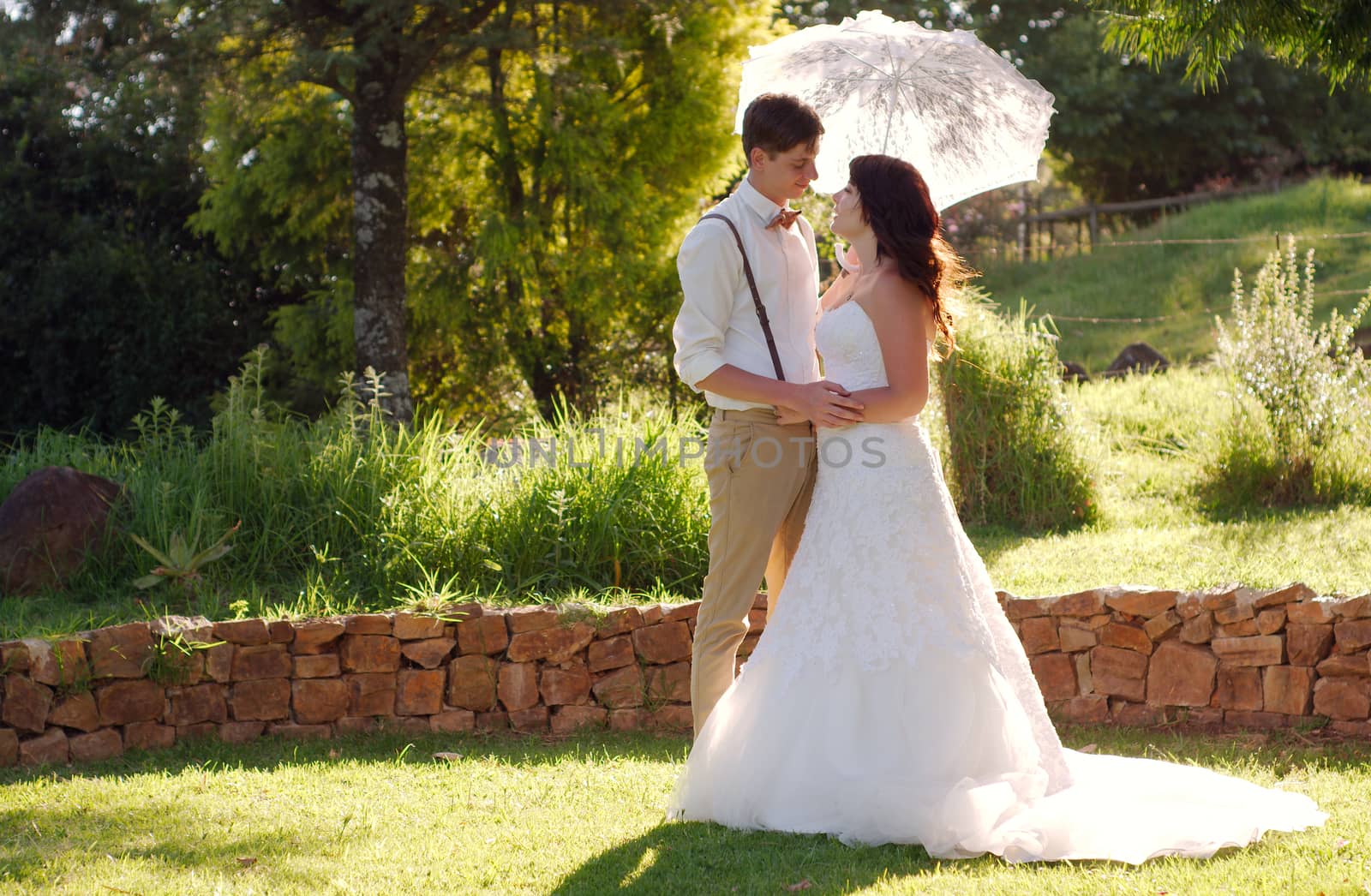 Bride and groom with parasol outside garden wedding ceremony