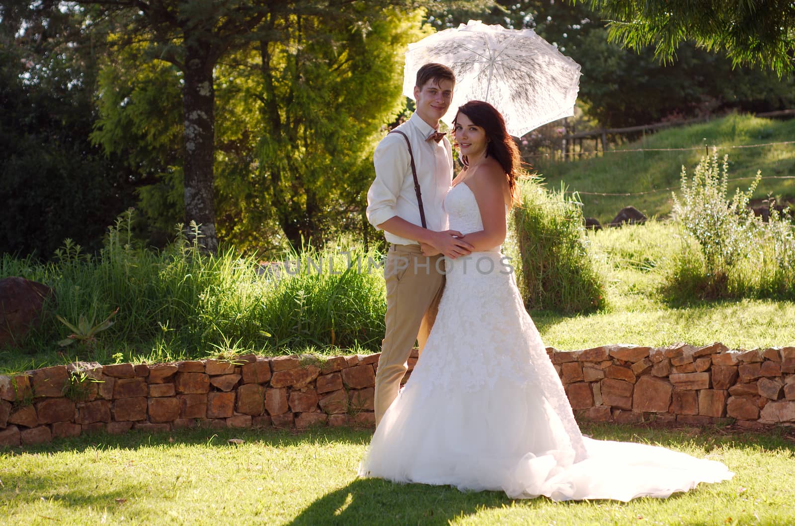 Bride and groom with parasol outside garden wedding ceremony