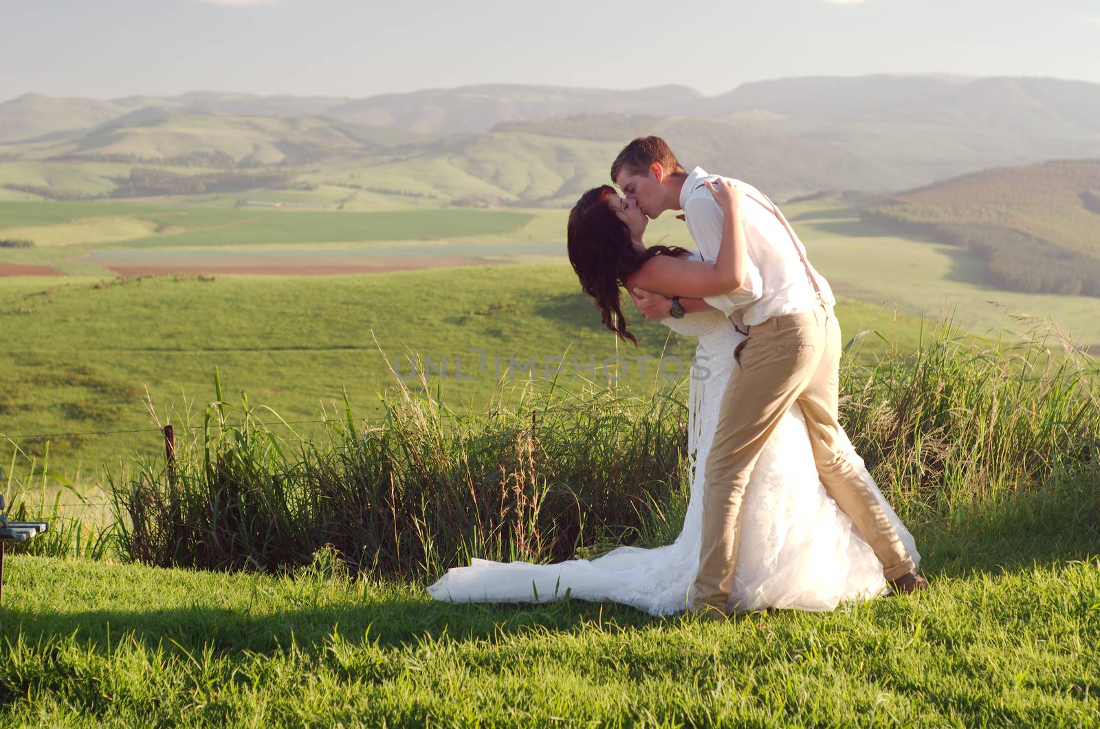 Bride and groom outside garden wedding with African Natal Midlands mountain scenery background
