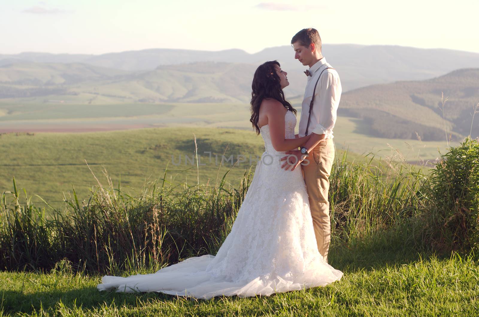 Bride and groom outside garden wedding with African Natal Midlands mountain scenery background