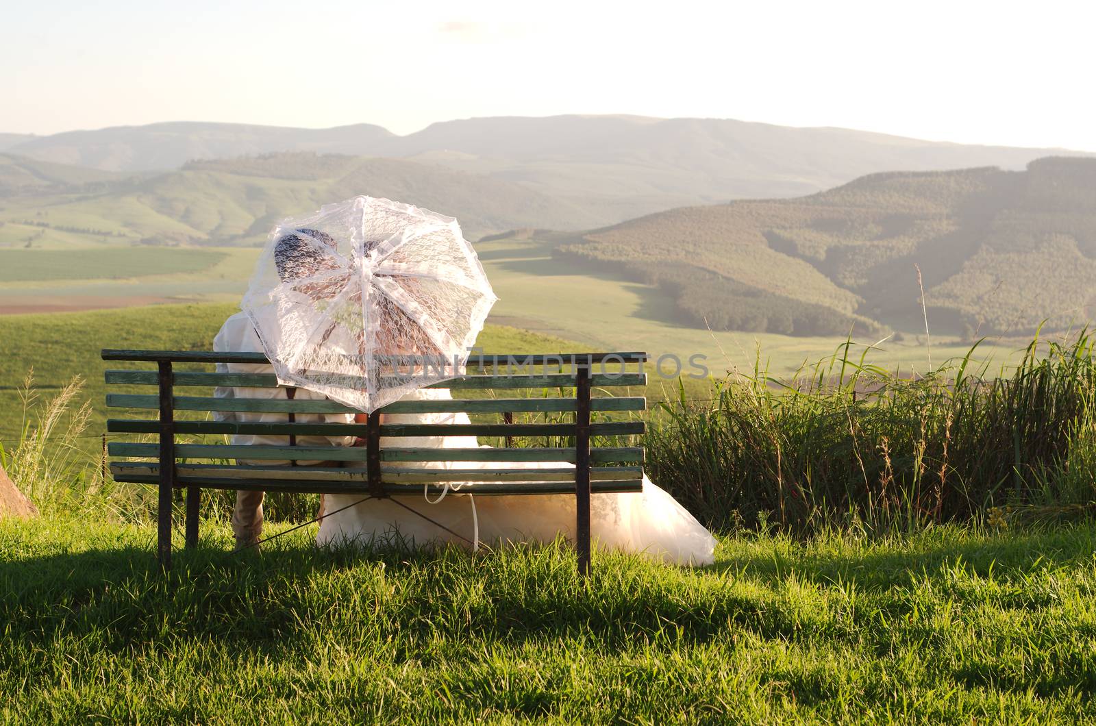 African bride and groom on bench with landscape by alistaircotton