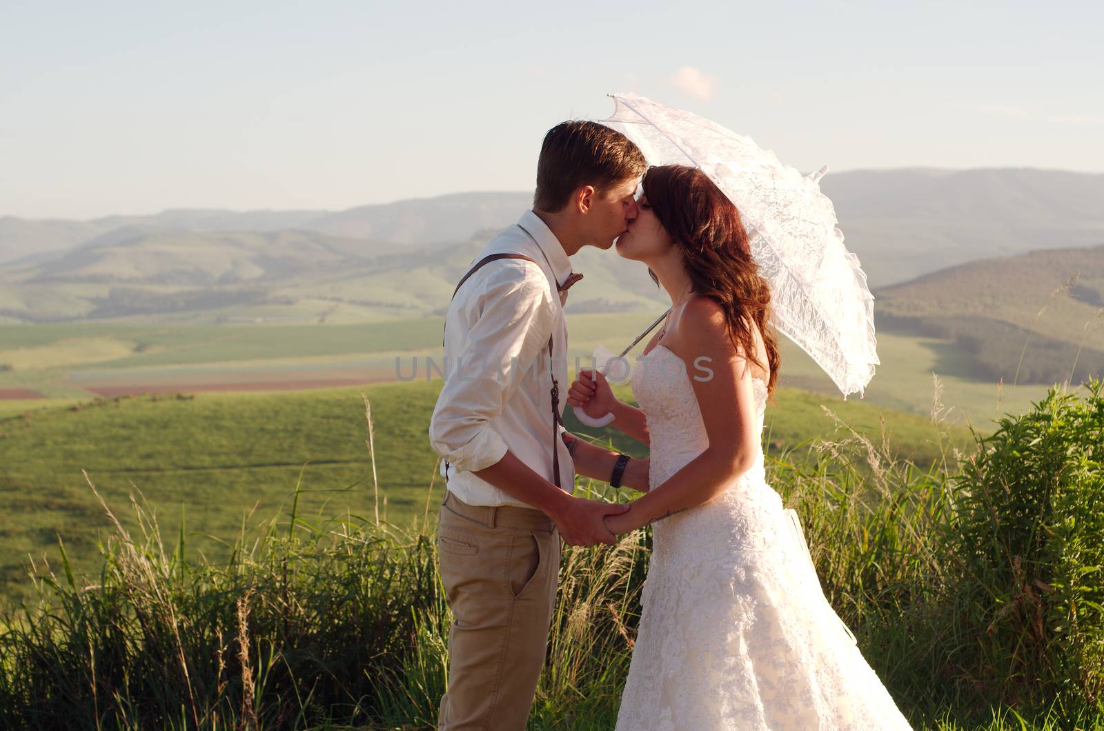 Bride and groom outside garden wedding with African Natal Midlands mountain scenery background