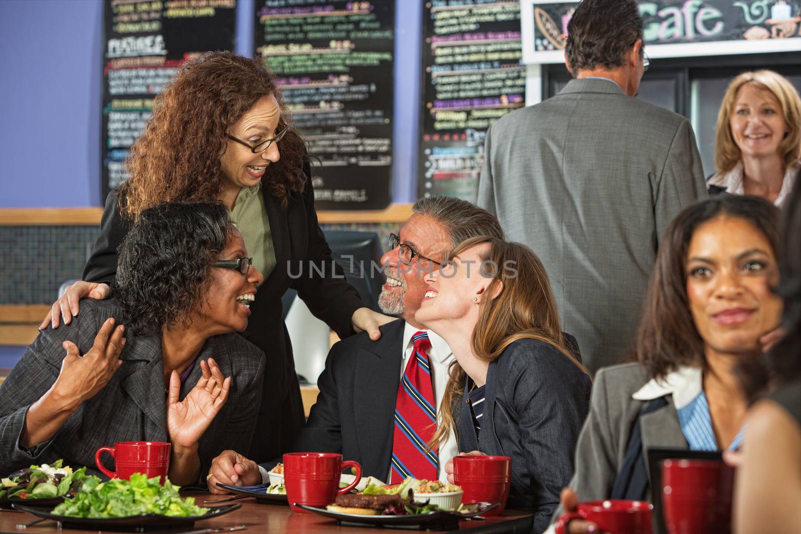 Four businesspeople laughing together during lunch in cafe