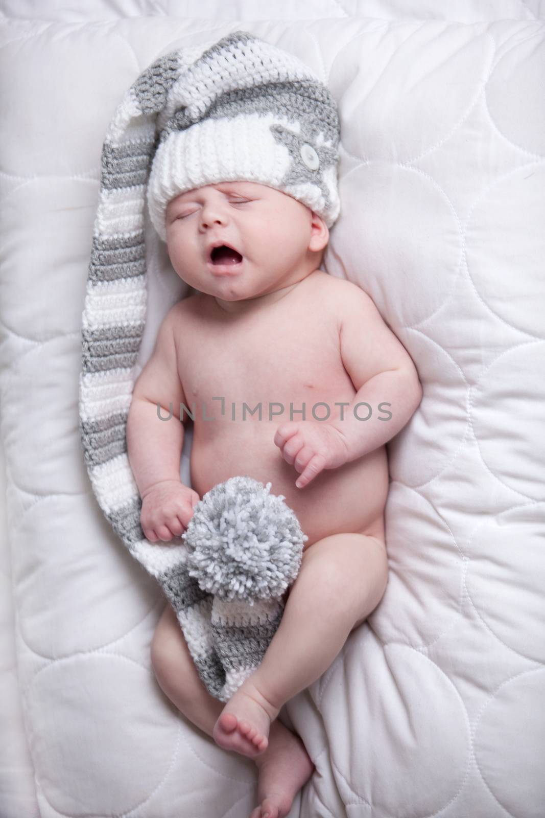 Baby with cap is yawning on a blanket by DNFStyle