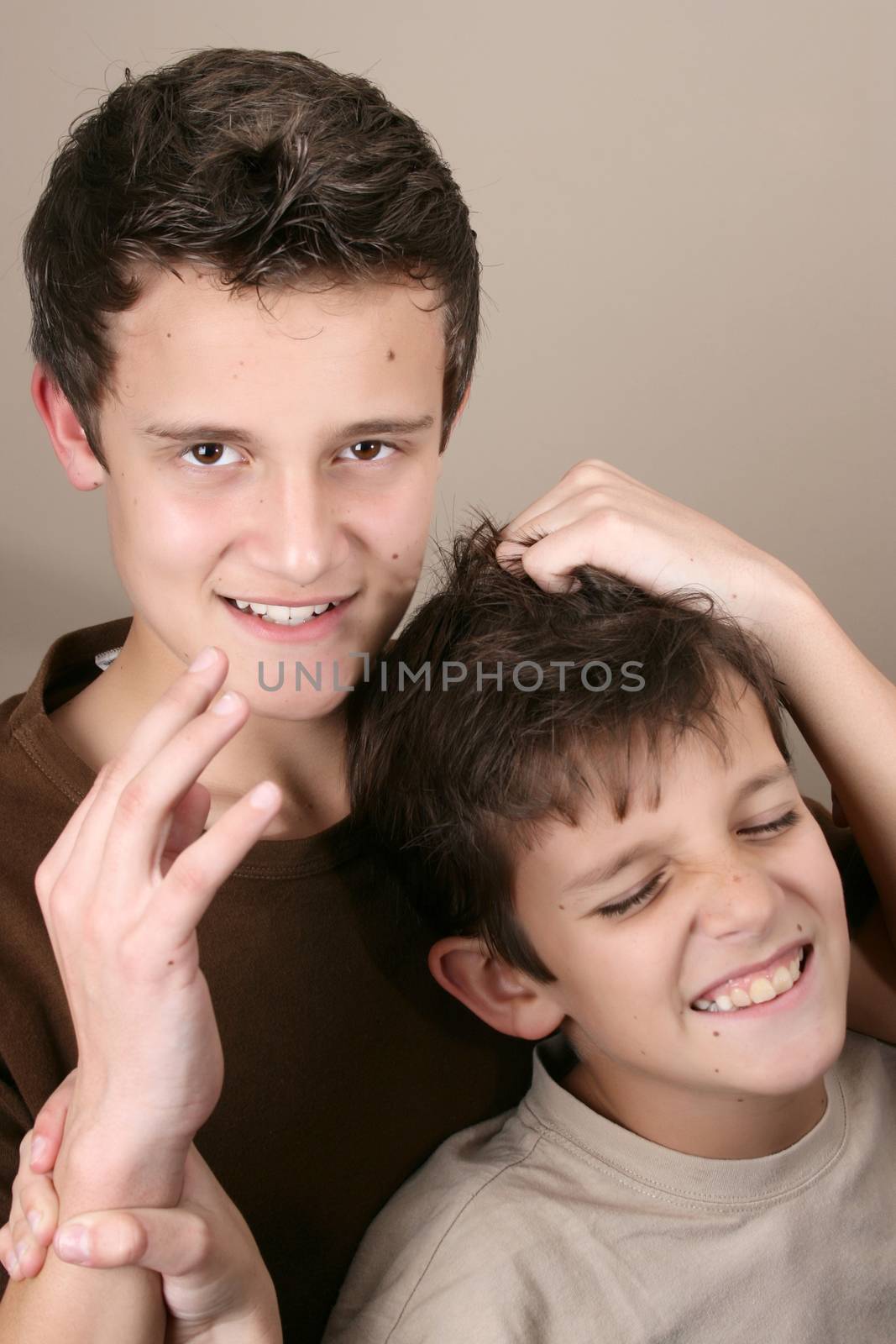 Two boys playing rough against brown background