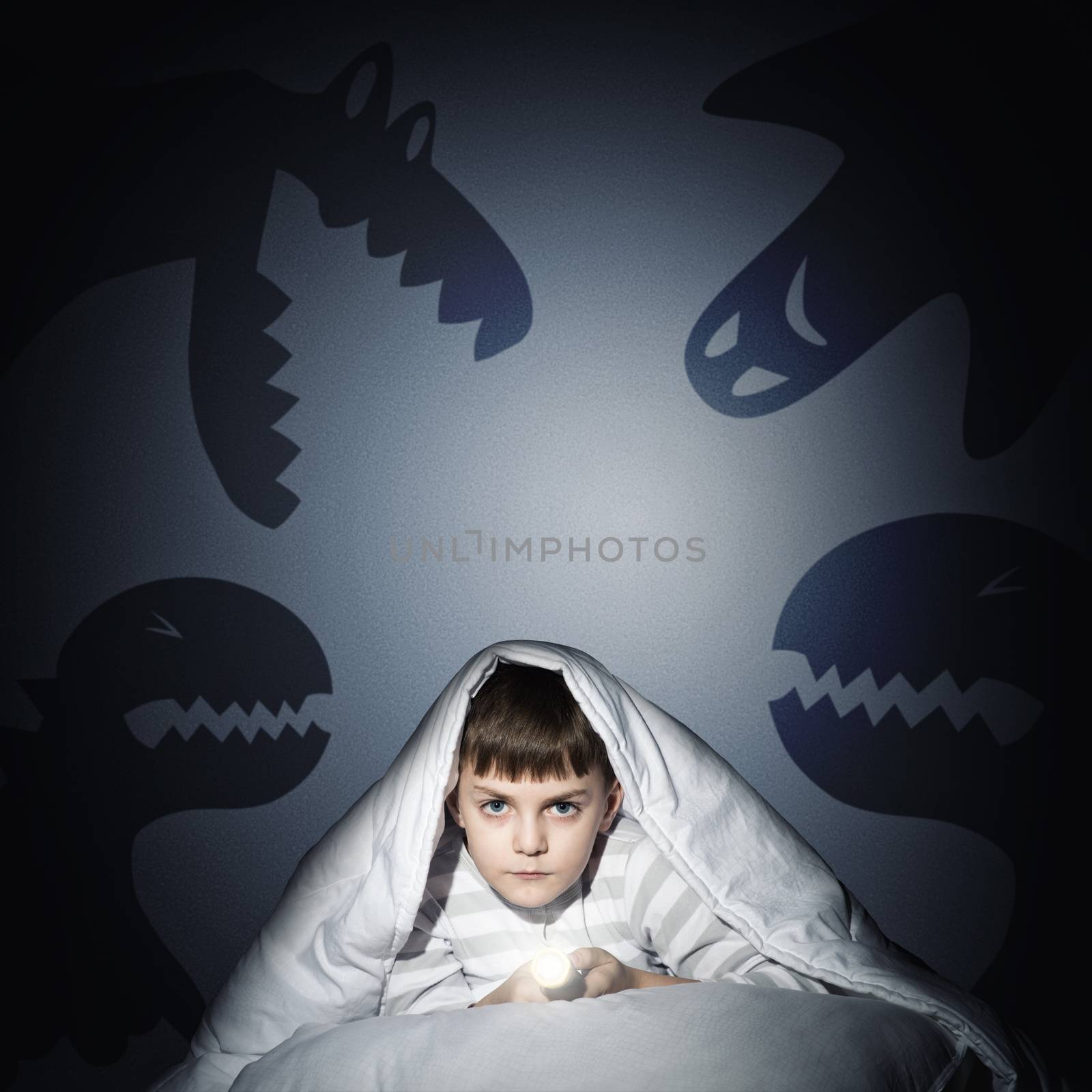 image of a boy under the covers with a flashlight the night afraid of ghosts