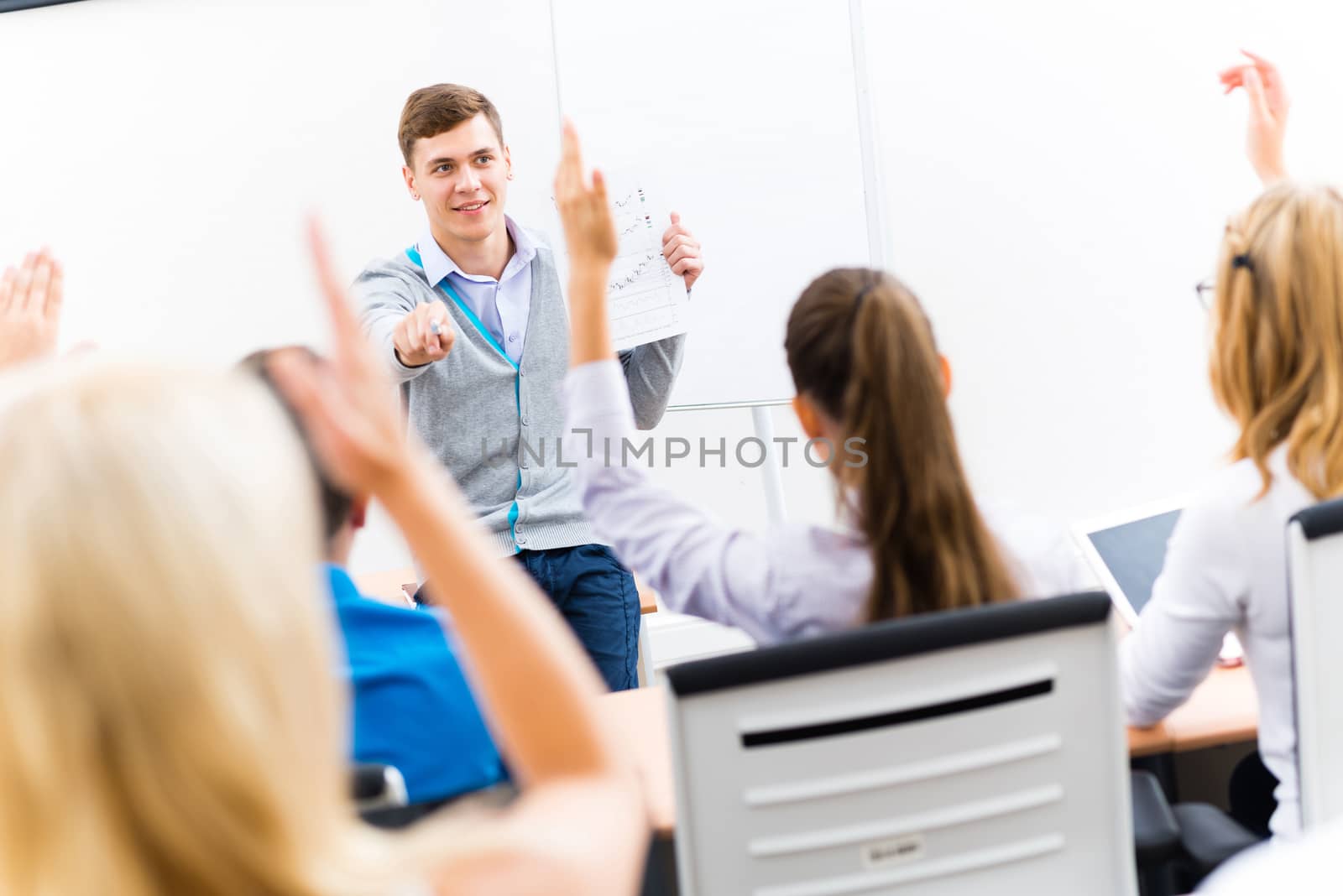 young teacher man talking with students in the classroom