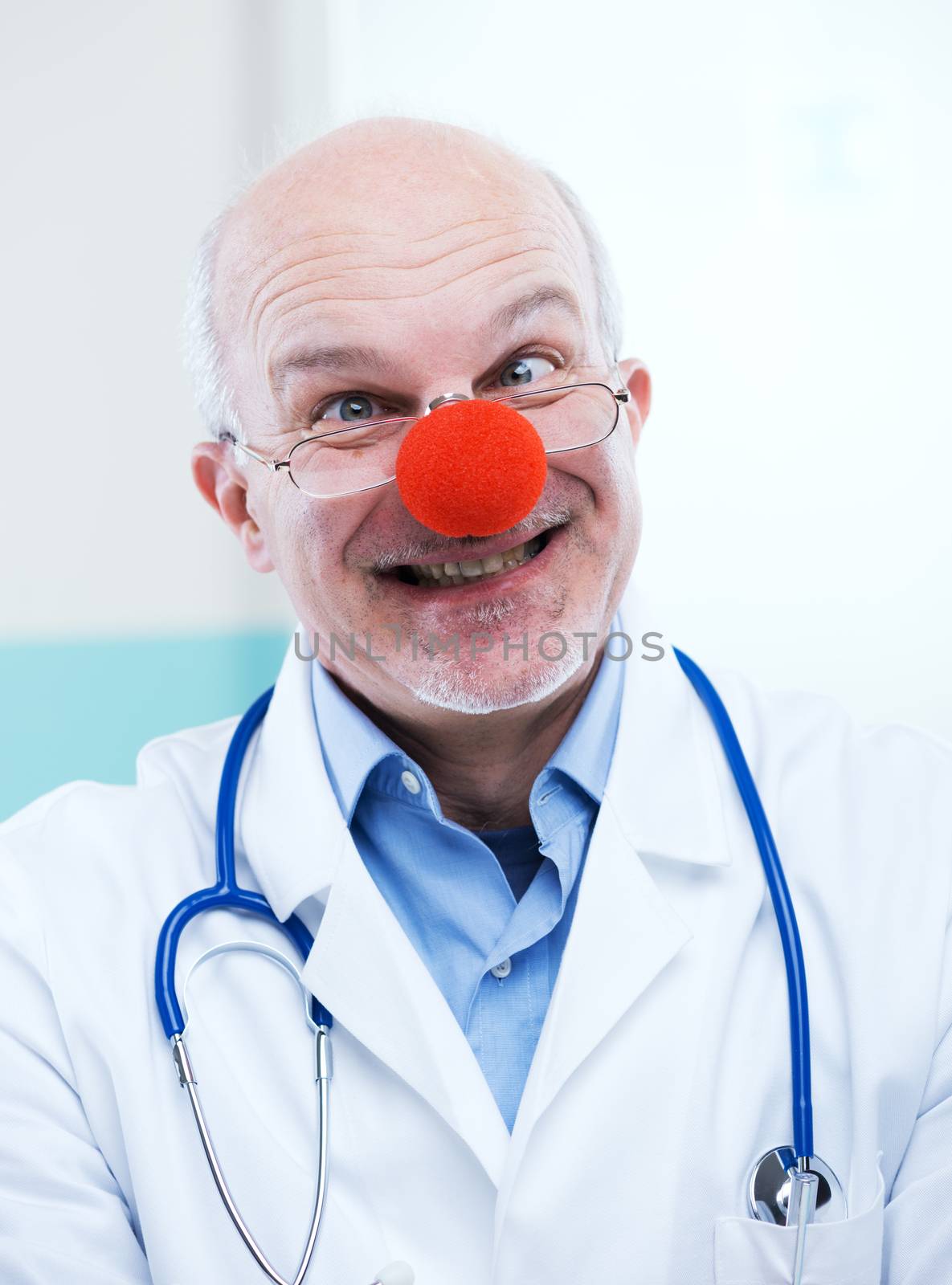 Funny senior doctor with red clown nose and funny expression.