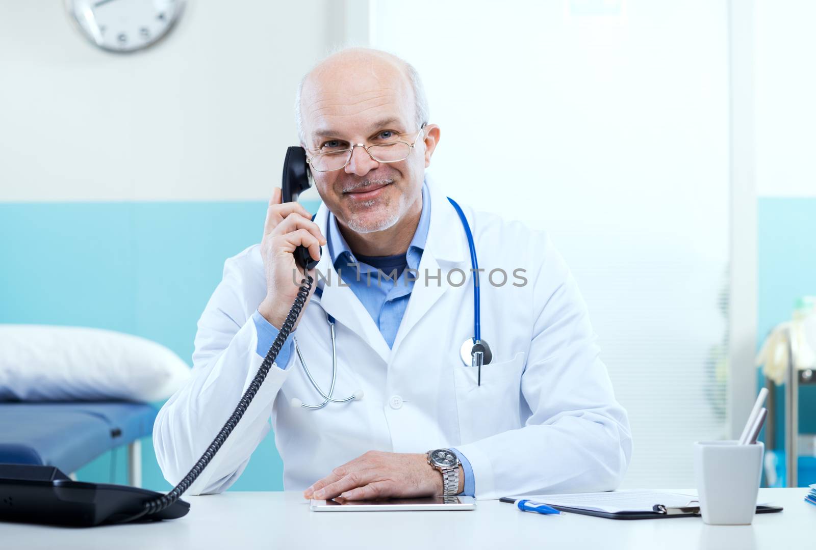 Doctor talking on the phone with medical equipment in the background.