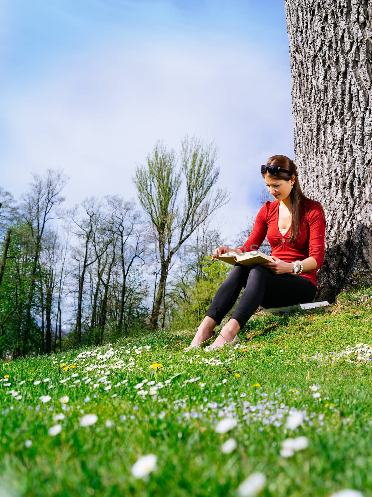 Young woman reading and enjoying spring by sumners