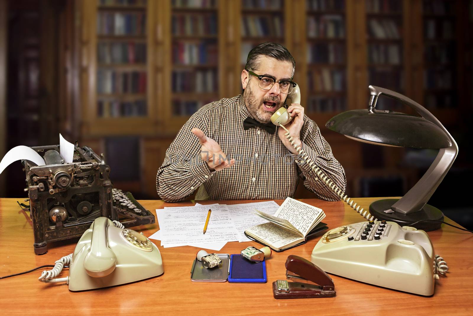 Employee with glasses talking on the phone in the office in the 1960s