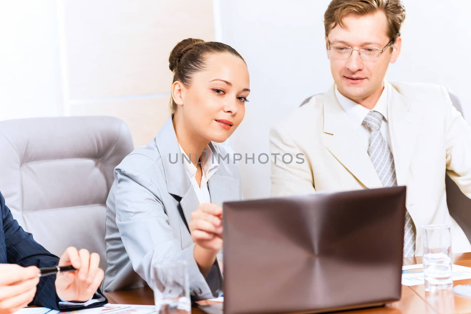 Business people talking, sitting at the table, watching the presentation on a laptop