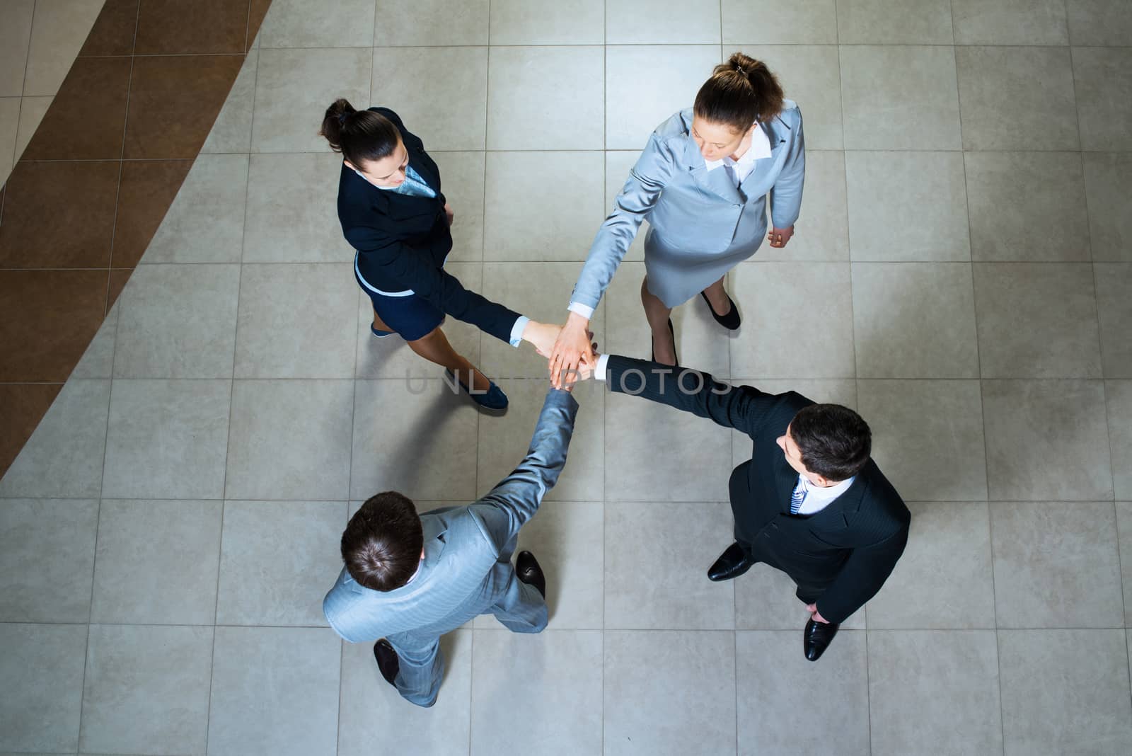 team of four businessmen with folded hands, a symbol of teamwork